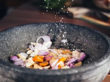 Schüssel mit Zwiebeln, Gewürzen und Salz im Mittelpunkt.