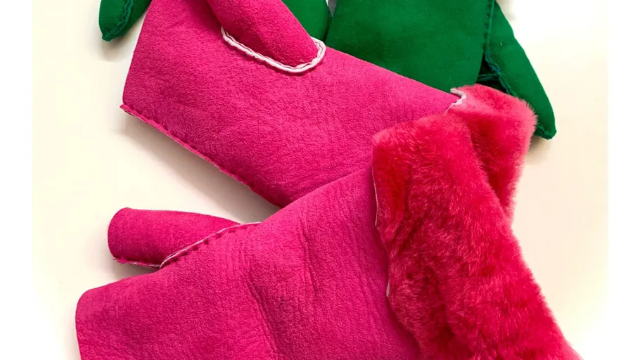 Pink and green mittens on a white surface.