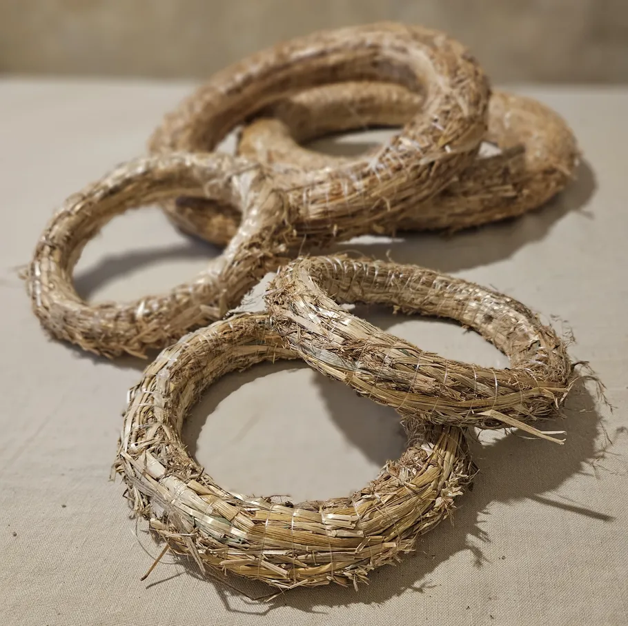 Straw wreaths stacked on a table.
