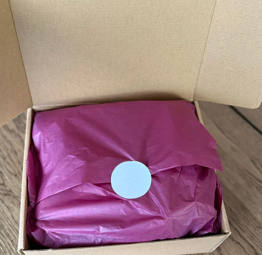 Offene Schachtel mit magentafarbenem Seidenpapier innen.