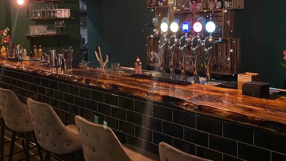 Gemütliche Bar mit Hockern und beleuchteten Zapfhähnen.