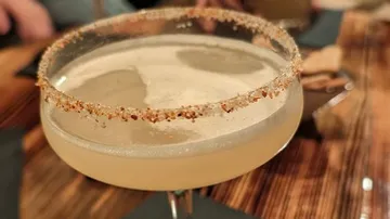 Cocktail glass with salted rim on table.