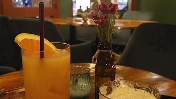 Cocktail und Blumen auf einem Holztisch.