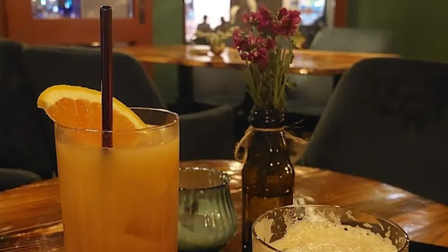 Cocktail und Blumen auf einem Holztisch.
