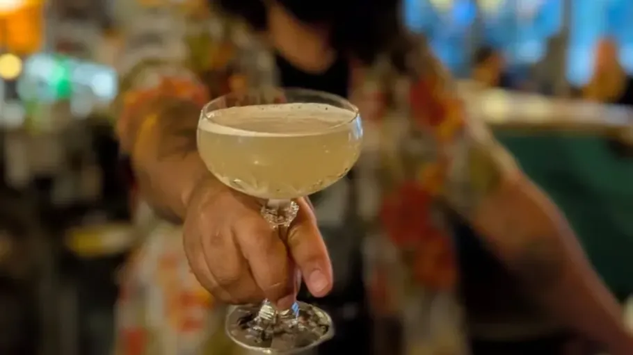 Person hält einen Cocktail in einer Bar.