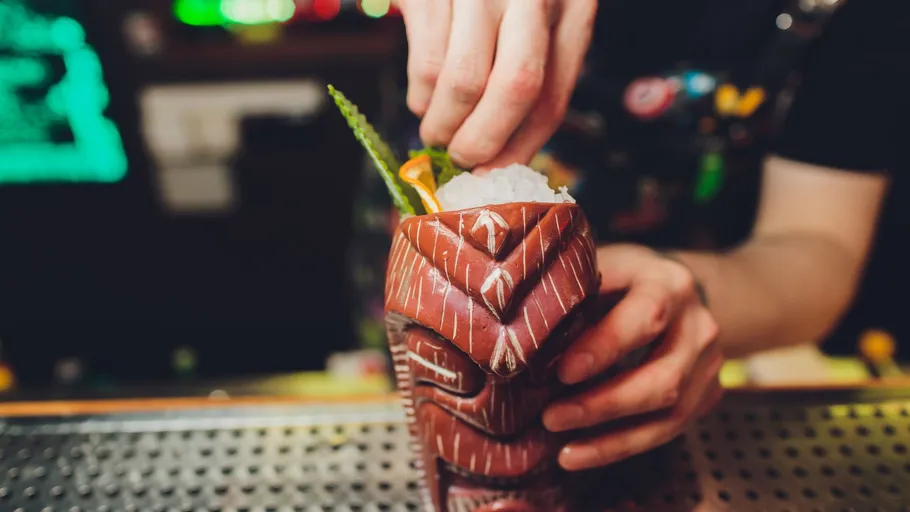 Hände bereiten Getränk in geschnitztem Becher vor.