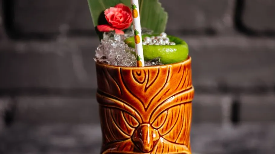 Tiki-Becher mit Cocktail, Eis, Garnitur; Ziegelhintergrund.