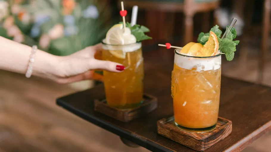 Hände platzieren Cocktails auf Holztisch.