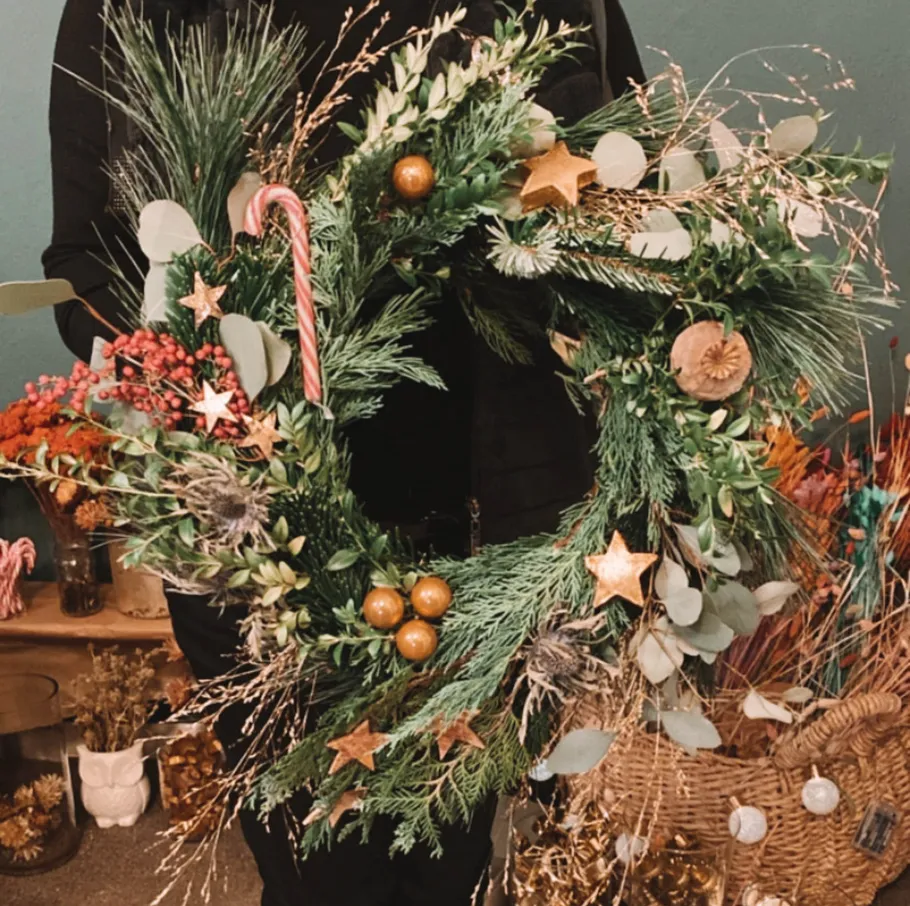 Decorated wreath held by person indoors.