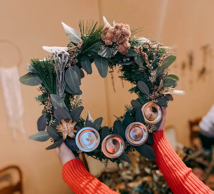 Hands holding decorative wreath, indoors.