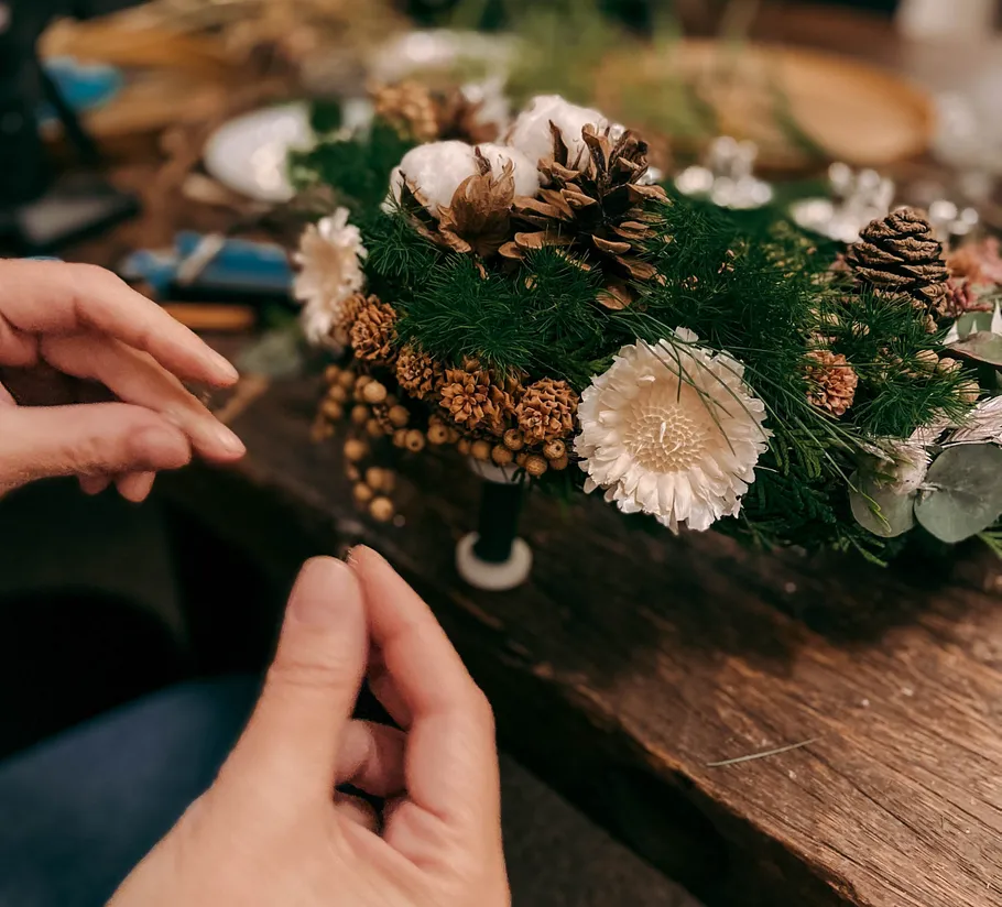 Hände arrangieren Blumen auf Holztisch.