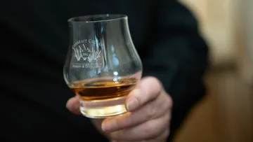 Hand hält Whiskyglas im Innenbereich.