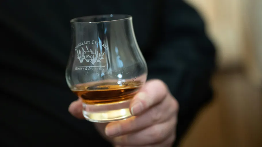Hand hält Whiskyglas im Innenbereich.