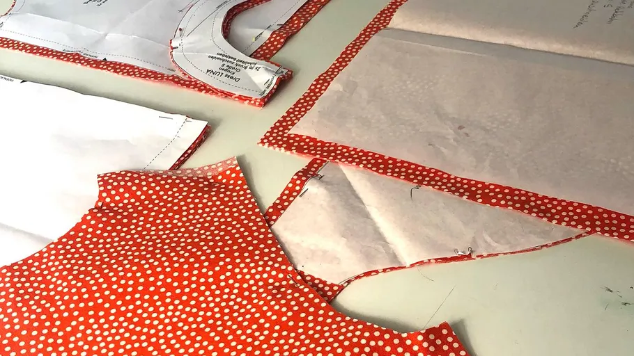 Schnittmusterstücke auf rotem Punktmusterstoff.