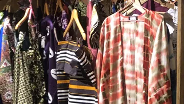 Bunte Kleidung an Holzkleiderbügeln.