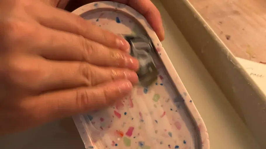 Hands polishing colorful terrazzo tray.