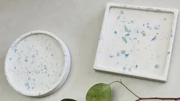 Two terrazzo coasters on a gray surface.