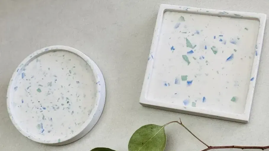 Two terrazzo coasters on a gray surface.
