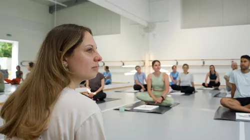 People sitting on yoga mats in a studio.
