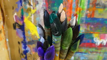 Paintbrushes held together with colorful paint splatters.