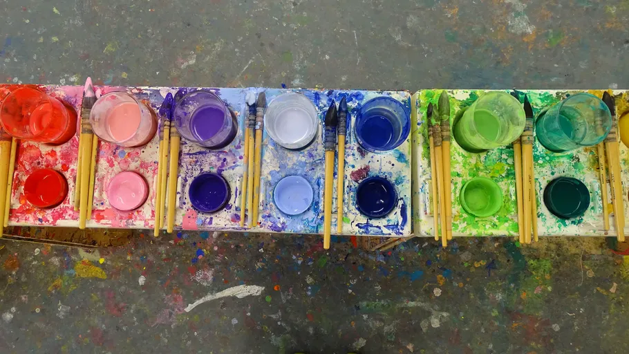 Paint pots and brushes on a splattered table.