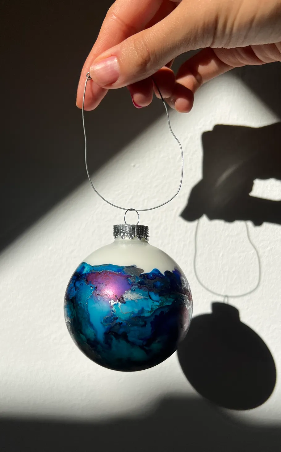 Hand holds decorative ornament against wall.