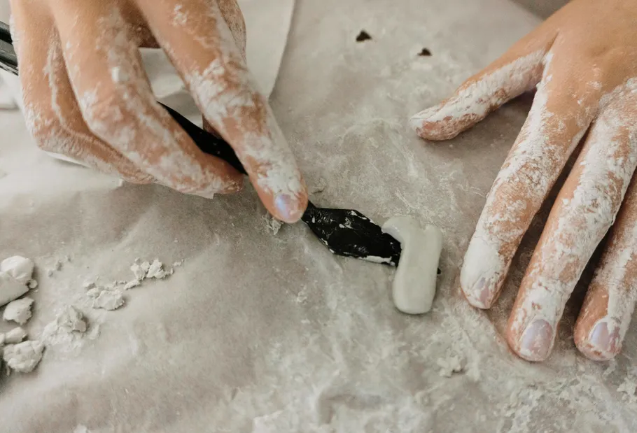 Hands shaping clay on a table.