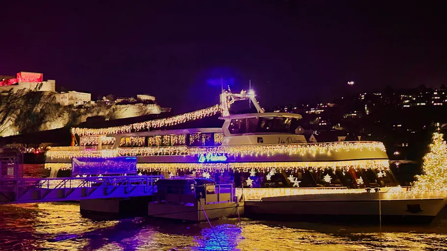 Boat decorated with lights near illuminated fortress.