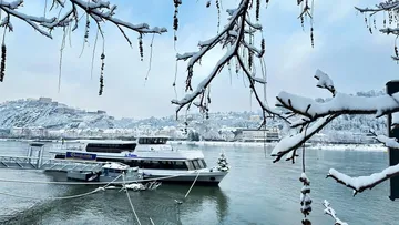 Boat docked on snowy riverbank in winter.