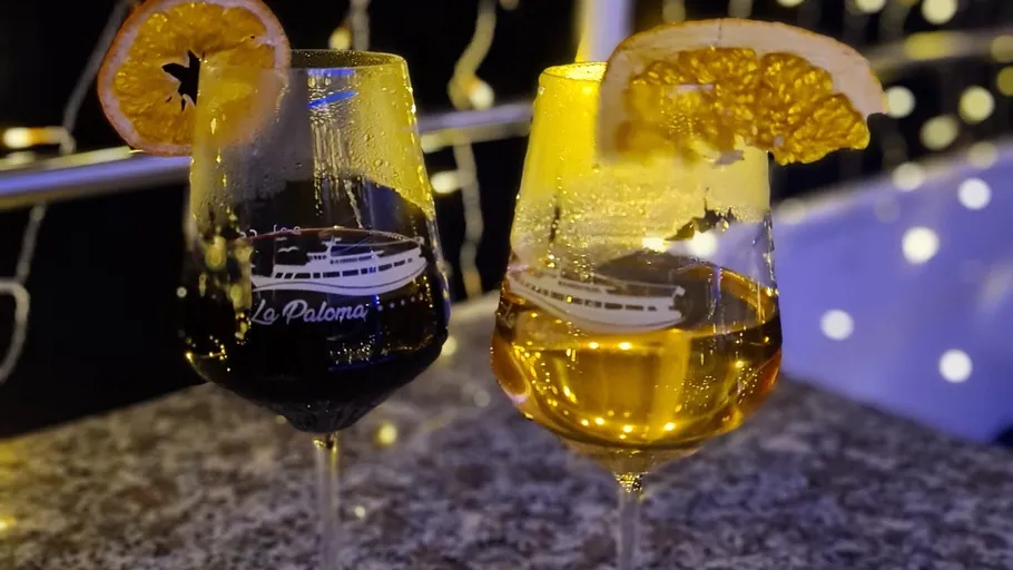 Two wine glasses with citrus garnish, night setting.