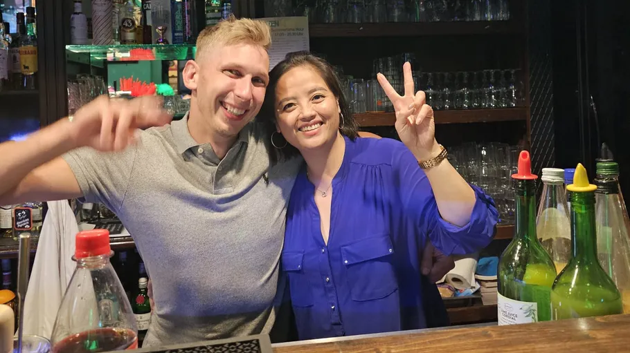 Two people smiling behind a bar counter.