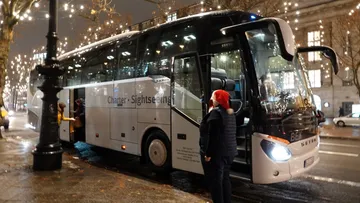 Charter bus stopped on city street at night.