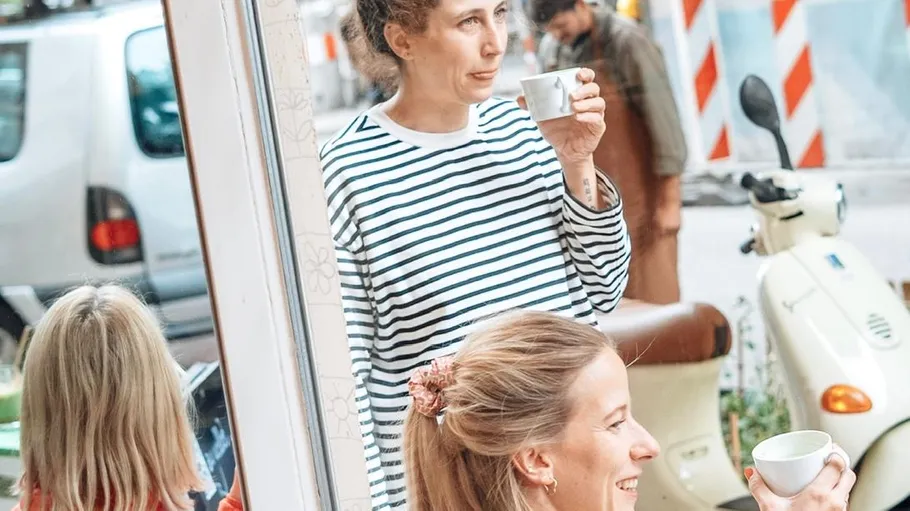 Women enjoying coffee outside cafe.