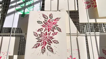 Colorful prints drying on metal rack.