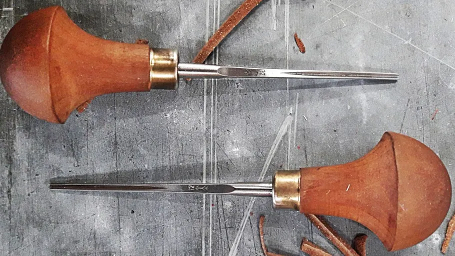 Two awls on a textured surface.