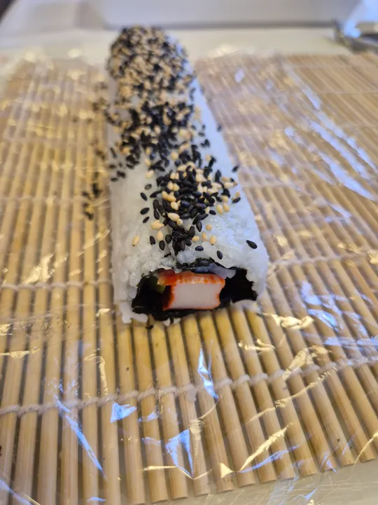 Sushirolle mit Sesam auf Bambusmatte.