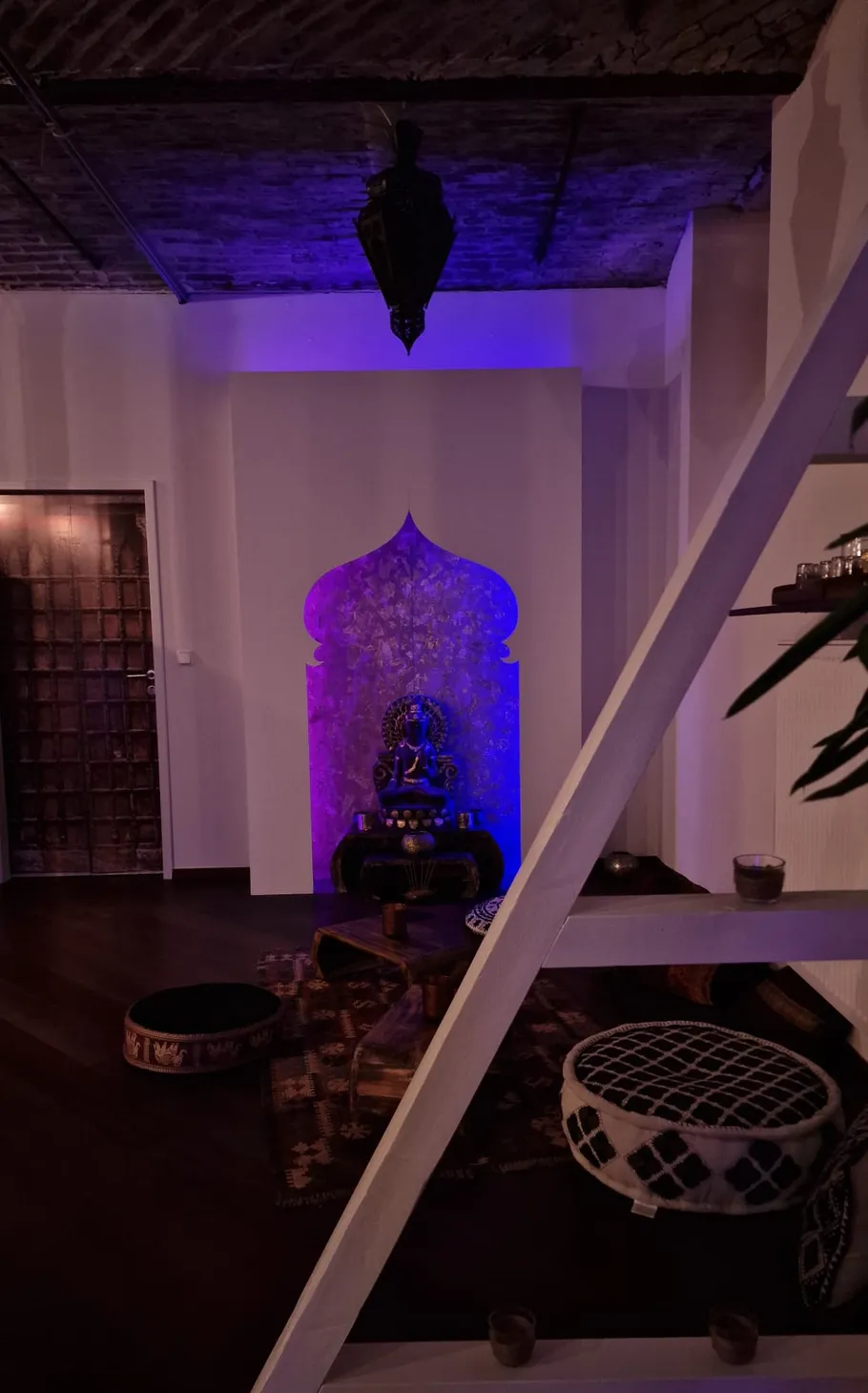 Buddha statue with blue lighting in room.