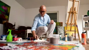 Man painting on floor in art studio.