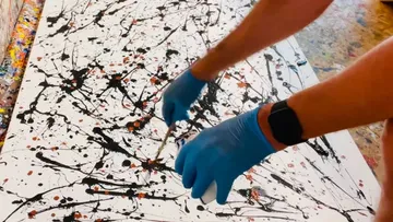 Person spritzt Farbe mit blauen Handschuhen.
