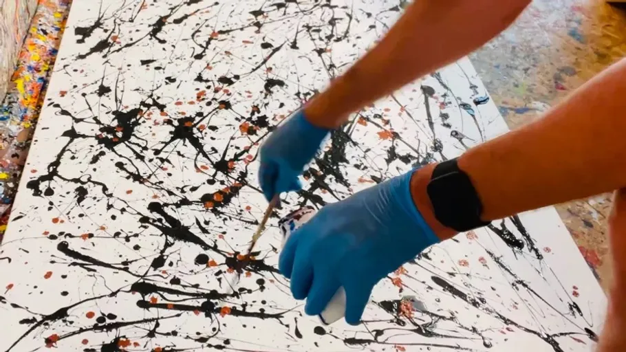 Person spritzt Farbe mit blauen Handschuhen.