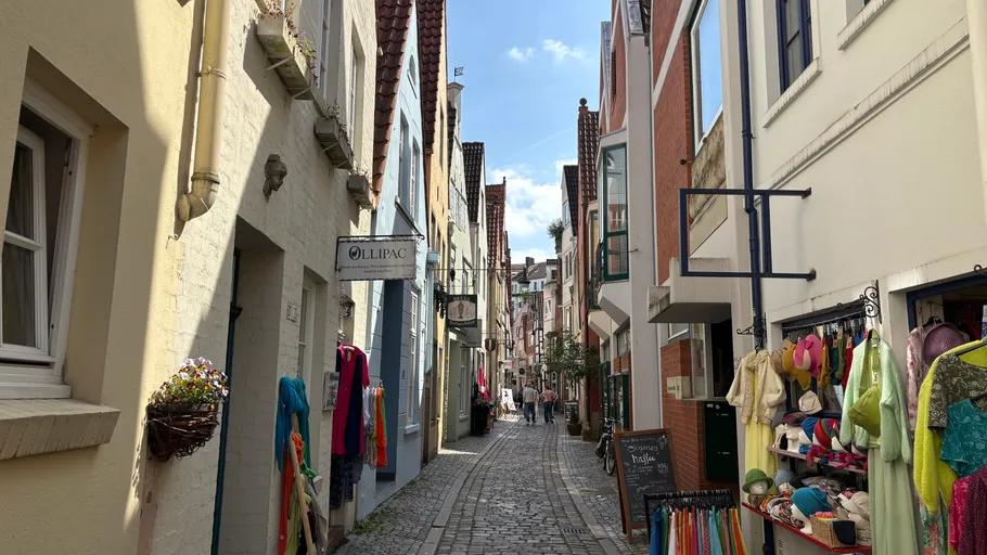 Narrow cobblestone street with colorful shops.