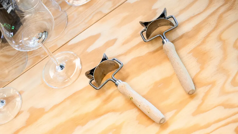 Pizza cutters and glasses on wooden table.