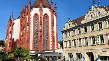 Historische rote Kirche neben verziertem Gebäude, sonniger Tag.