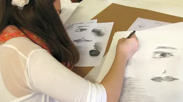 Person sketching faces on paper.