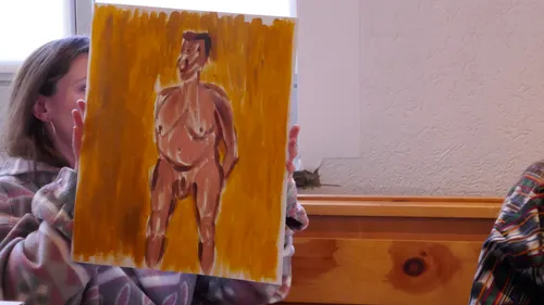Person holding painting of nude figure indoors.