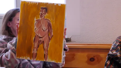 Person hält Gemälde einer nackten Figur drinnen.