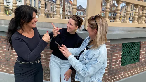 Three women conversing outdoors by a railing.