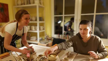 Zwei Frauen decken den Tisch in Küche.