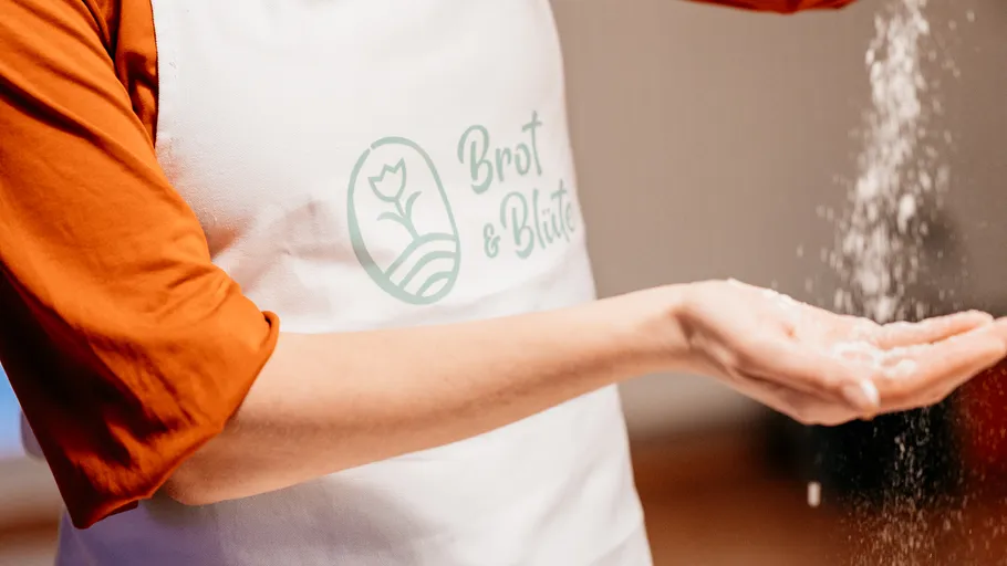 Person streut Mehl in der Küche.