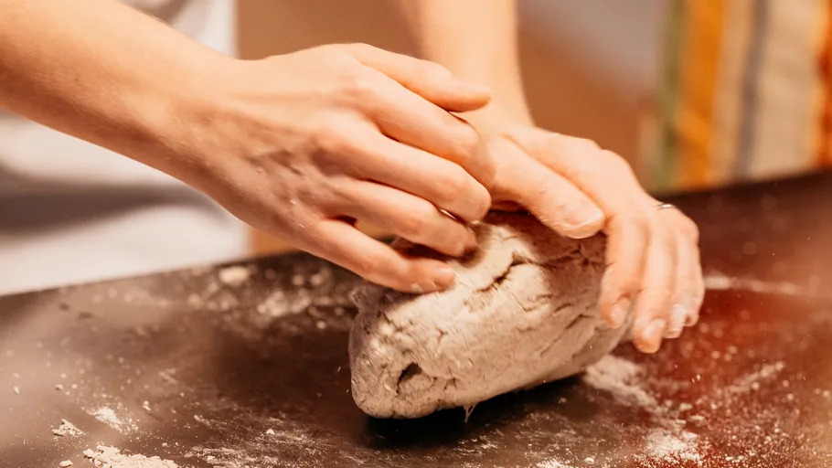 Hands kneading dough on a floured surface.